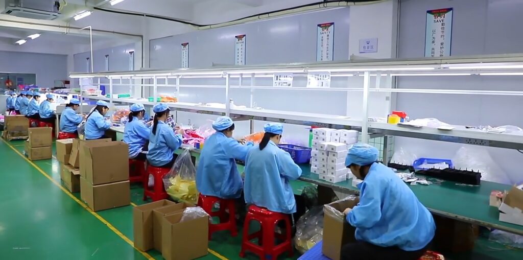 Workers on silicone product packaging line in controlled environment for clean shipment