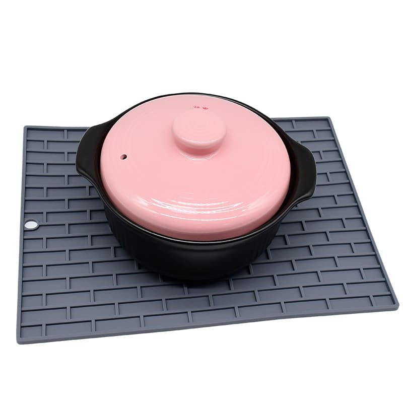Textured silicone drying mat used under cookware for drainage, heat protection, and countertop safety