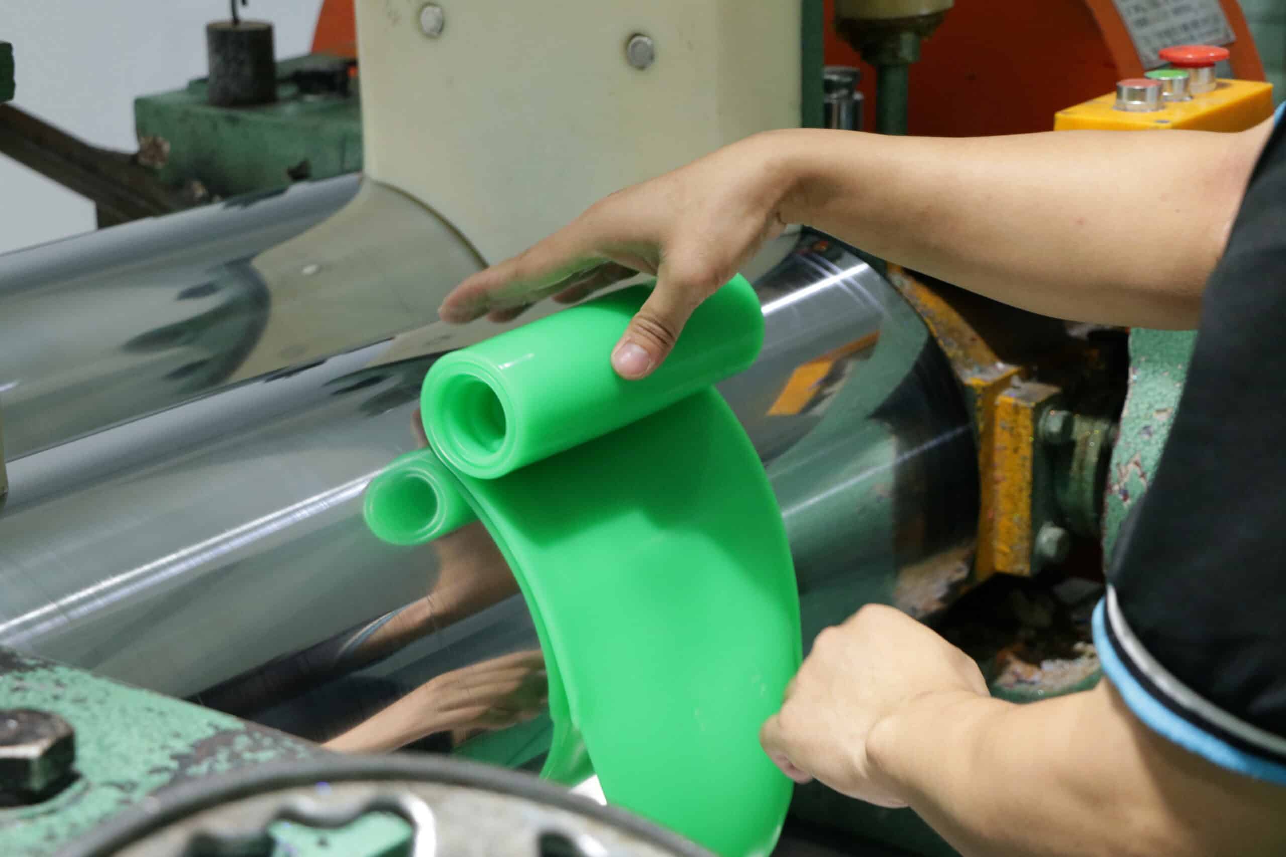 Operator inspecting green silicone sheet during custom silicone part production
