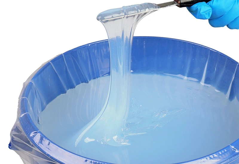 Blue liquid silicone rubber being handled with a spatula, ready for molding