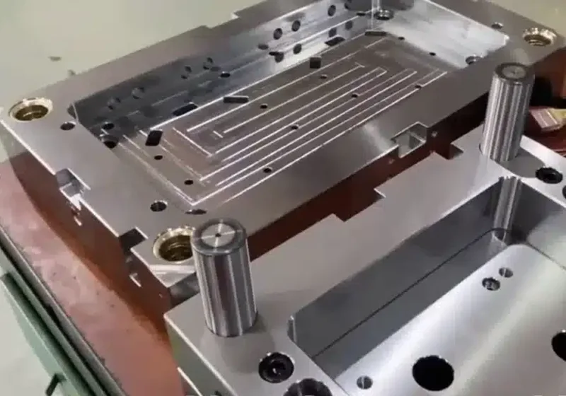 Technician's hands assembling and adjusting a precision steel mold on a workbench using tools in a clean workshop