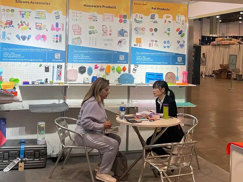 Balle Zhong speaking with a client at a trade show about custom silicone products and manufacturing solutions